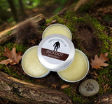 Three tins of Bigfoot Beard Balm on a natural background with leaves and wood.