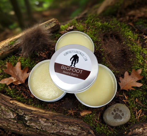 Three tins of Bigfoot Beard Balm on a natural background with leaves and wood.