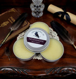 Three tins of 'Nevermore Beard Balm' on a wooden surface with decorative items.