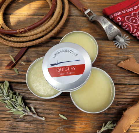Quigley beard balm tins on a wooden surface with rustic items.
