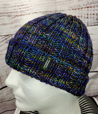 Hat displayed on male mannequin head. Colors of the hat are primarily blue and green with tones of purple brown and yellow