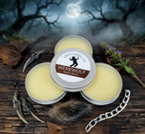 Three tins of Werewolf Beard Balm on a wooden surface with a moonlit night background.